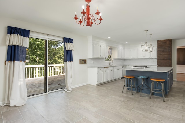 kitchen featuring pendant lighting, backsplash, white cabinetry, a kitchen breakfast bar, and an inviting chandelier