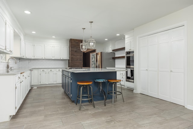 kitchen featuring hanging light fixtures, white cabinets, a kitchen island, stainless steel appliances, and a kitchen bar