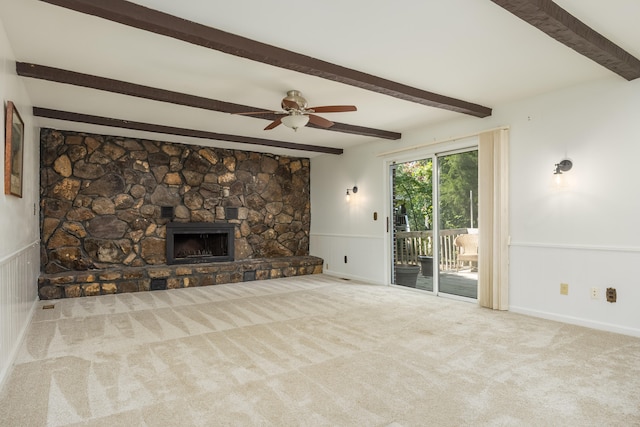 unfurnished living room featuring ceiling fan, beamed ceiling, a fireplace, and light carpet