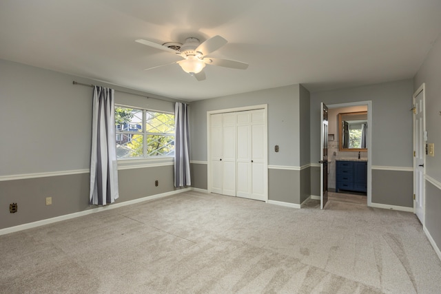 unfurnished bedroom with light carpet, a closet, ceiling fan, and connected bathroom