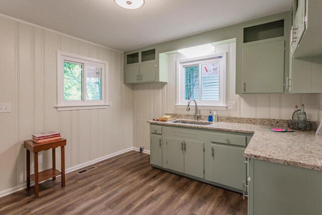 kitchen with light stone countertops, green cabinetry, dark hardwood / wood-style floors, and sink