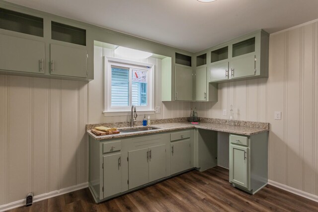 kitchen with light stone countertops, green cabinetry, sink, and dark wood-type flooring