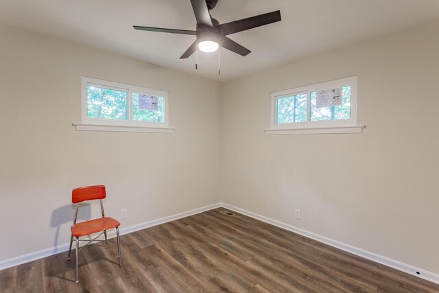 empty room with a healthy amount of sunlight, dark hardwood / wood-style flooring, and ceiling fan