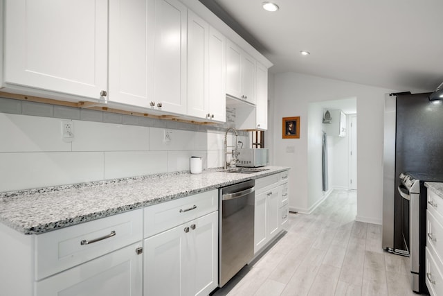 kitchen featuring backsplash, sink, light stone countertops, appliances with stainless steel finishes, and white cabinetry