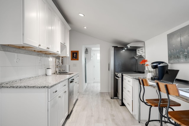 kitchen featuring sink, tasteful backsplash, light stone counters, white cabinets, and appliances with stainless steel finishes