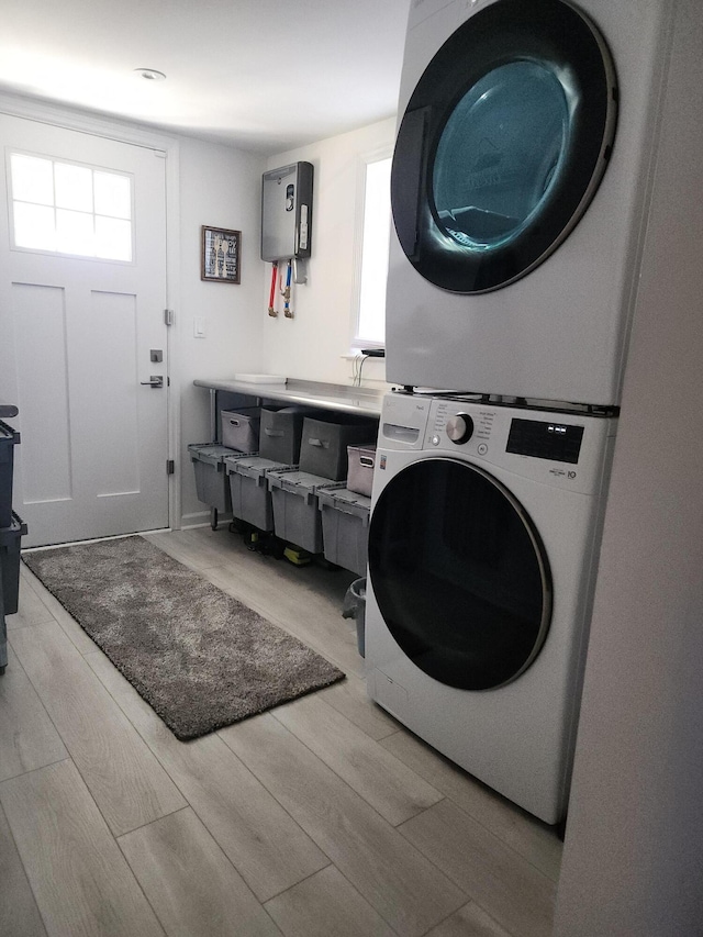 clothes washing area featuring stacked washer / dryer and light hardwood / wood-style flooring