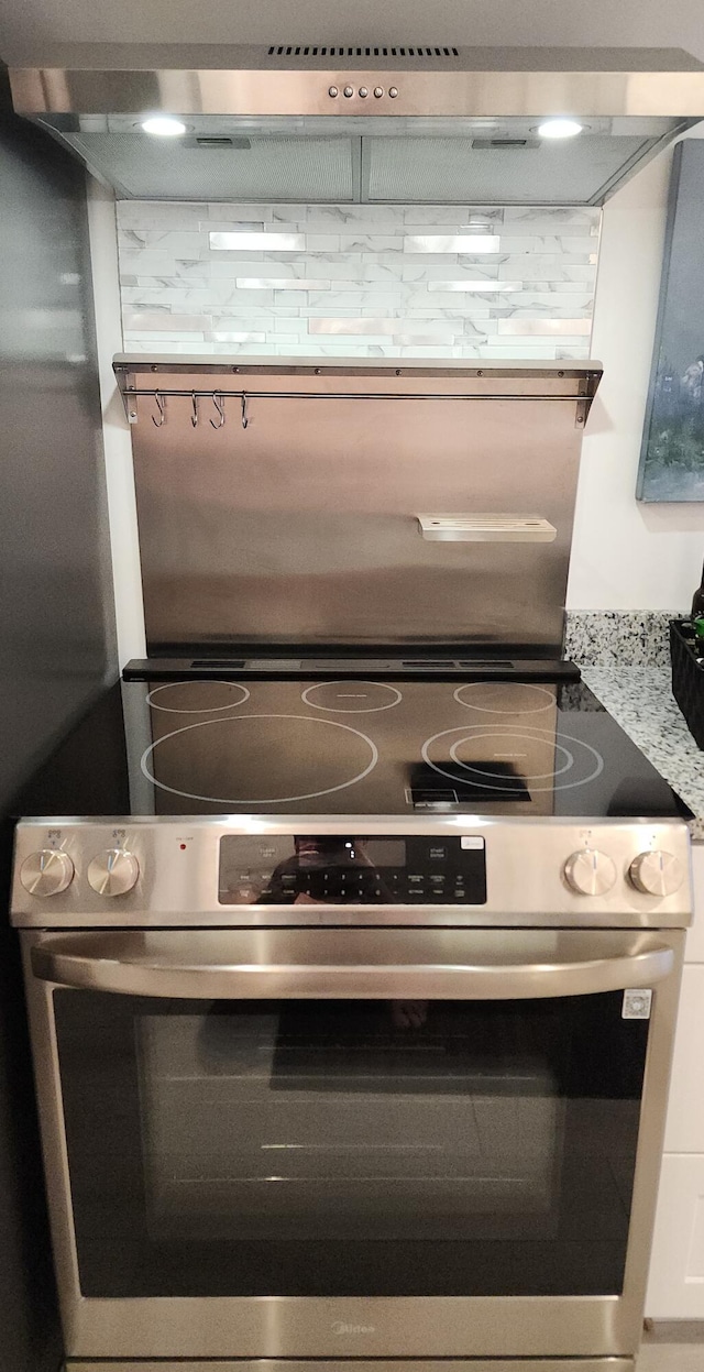 details featuring white cabinets, light stone countertops, ventilation hood, and stainless steel electric stove