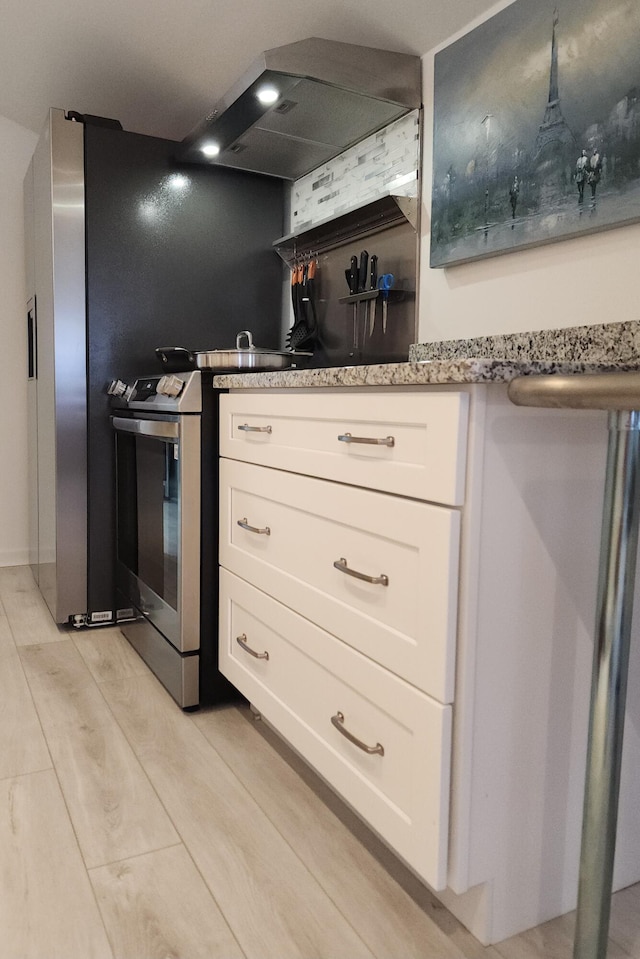 kitchen with light wood-type flooring, stainless steel stove, and white cabinetry