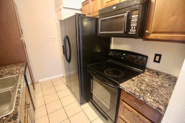 kitchen with black appliances, dark stone countertops, and light tile patterned flooring