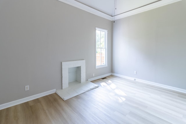 unfurnished living room featuring ornamental molding, light wood-type flooring, and a brick fireplace