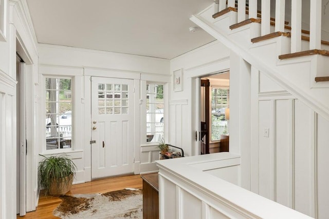 entrance foyer with ornamental molding and light hardwood / wood-style flooring