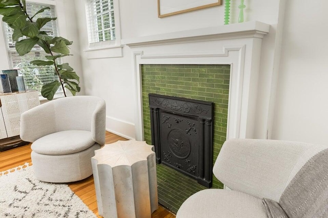 living area with a brick fireplace and wood-type flooring