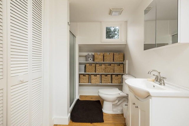 bathroom with walk in shower, vanity, toilet, and wood-type flooring