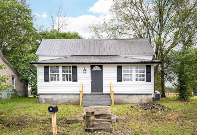 view of front of home with central AC unit and a front yard