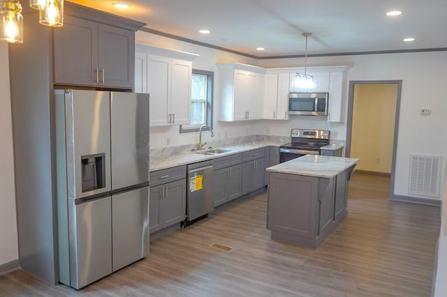 kitchen featuring pendant lighting, stainless steel appliances, a center island, and gray cabinets