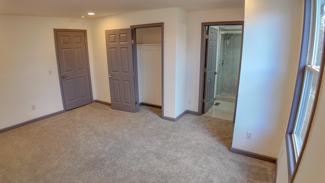 unfurnished bedroom with multiple windows, connected bathroom, and light colored carpet