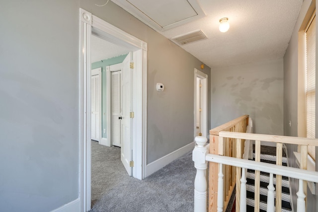 hall with a textured ceiling and carpet