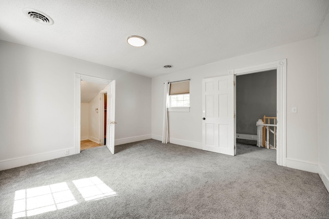 unfurnished bedroom with a textured ceiling and light colored carpet