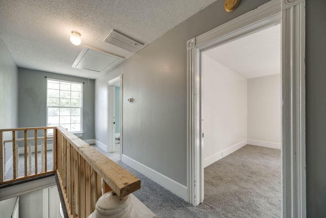 corridor with a textured ceiling and carpet