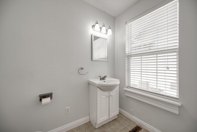 bathroom featuring vanity, a textured ceiling, a healthy amount of sunlight, and tile patterned floors