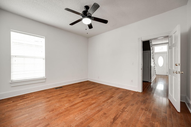 empty room with a textured ceiling, ceiling fan, and wood-type flooring