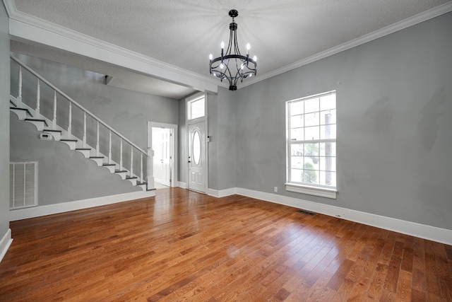 foyer entrance with a textured ceiling, crown molding, an inviting chandelier, and hardwood / wood-style floors