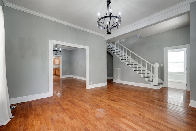 interior space with ornamental molding, a textured ceiling, hardwood / wood-style floors, and an inviting chandelier