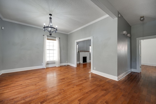 unfurnished room featuring a textured ceiling, a notable chandelier, hardwood / wood-style floors, and a brick fireplace