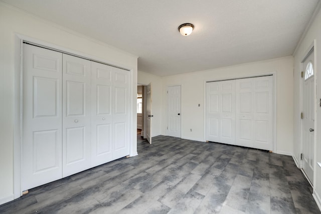 unfurnished bedroom featuring wood-type flooring, a textured ceiling, and multiple closets