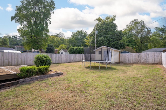 view of yard featuring a storage unit, a wooden deck, and a trampoline