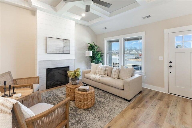 living room featuring a healthy amount of sunlight, ceiling fan, light hardwood / wood-style flooring, and a fireplace