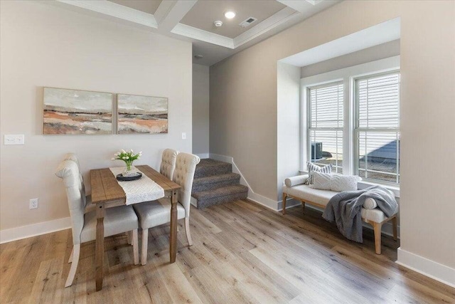 dining area with light hardwood / wood-style flooring, coffered ceiling, and beamed ceiling