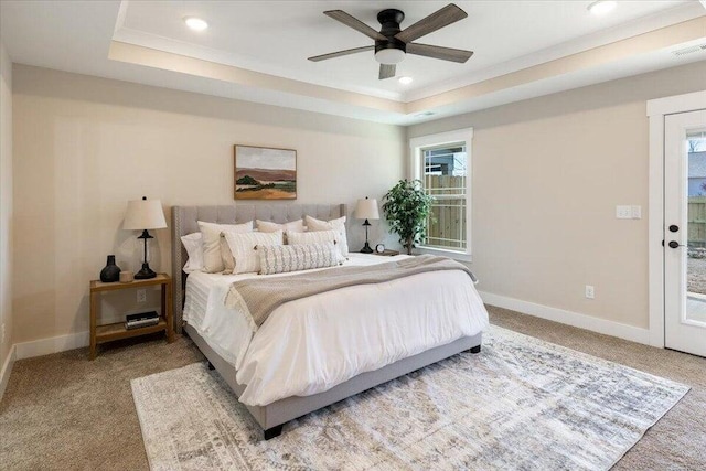 carpeted bedroom featuring a tray ceiling, access to exterior, and ceiling fan