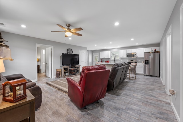 living room featuring ceiling fan and light hardwood / wood-style flooring