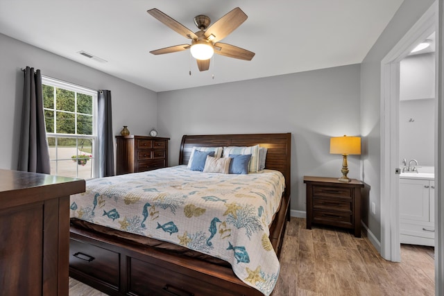 bedroom featuring light wood-type flooring, sink, ceiling fan, and ensuite bathroom