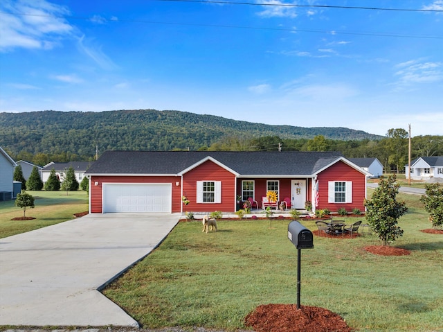 single story home with a mountain view, a front yard, and a garage