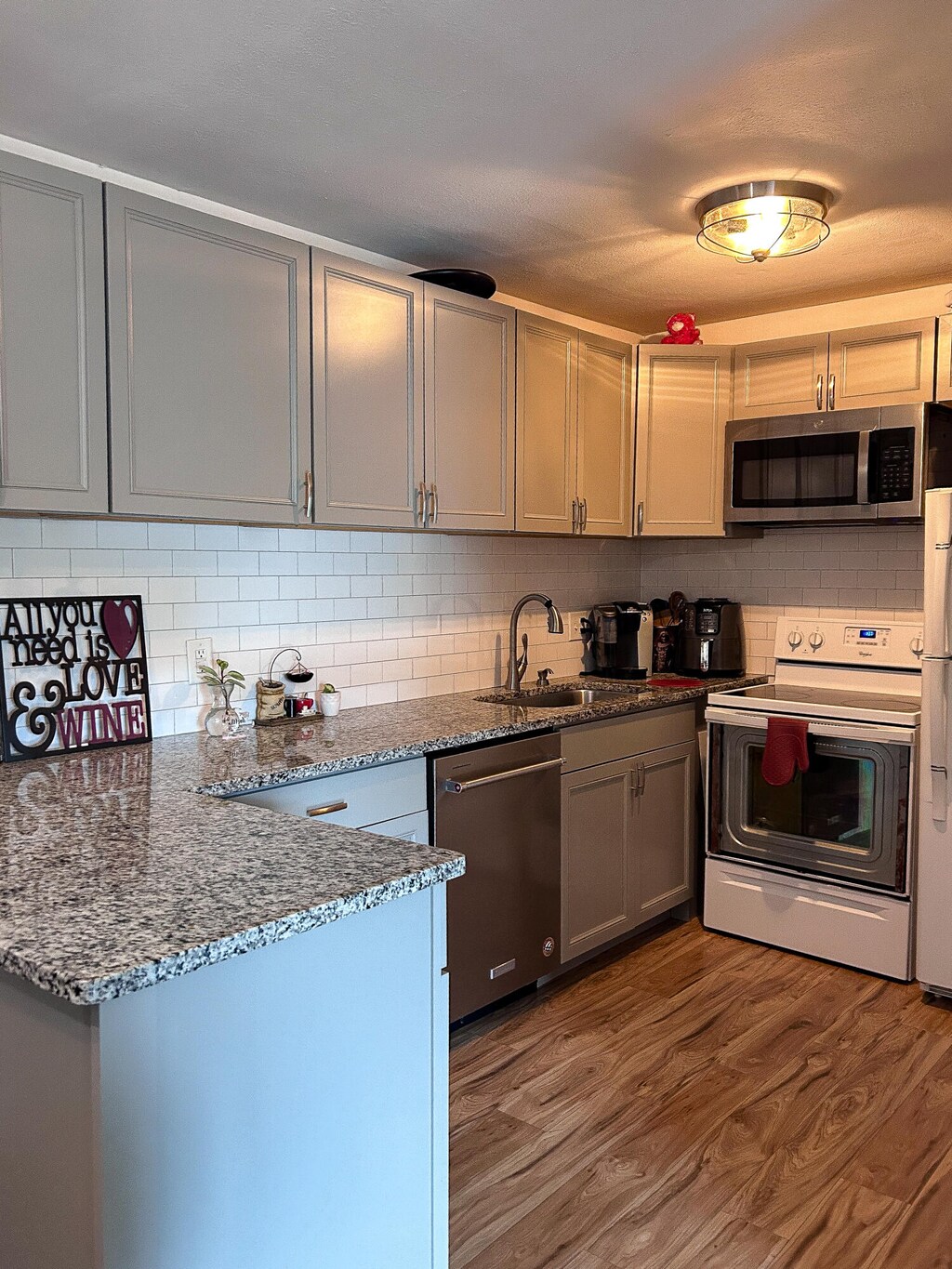 kitchen with gray cabinetry, wood-type flooring, appliances with stainless steel finishes, sink, and dark stone countertops