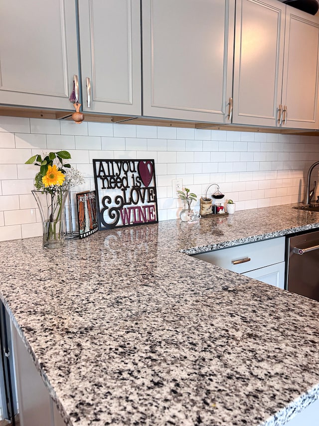 kitchen with gray cabinets, light stone counters, decorative backsplash, and sink