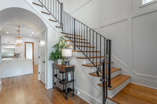 stairway featuring hardwood / wood-style floors, a notable chandelier, and sink