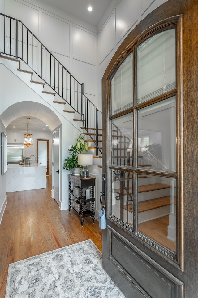 foyer with light wood-type flooring, a chandelier, and sink