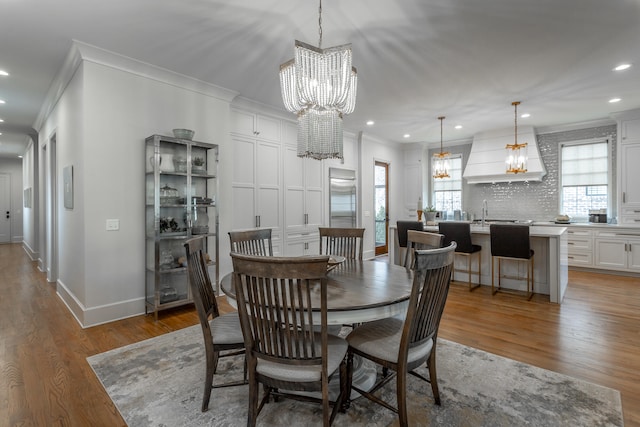 dining area with crown molding, hardwood / wood-style floors, and an inviting chandelier