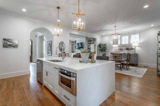 kitchen with sink, wood-type flooring, white cabinetry, and a kitchen island with sink