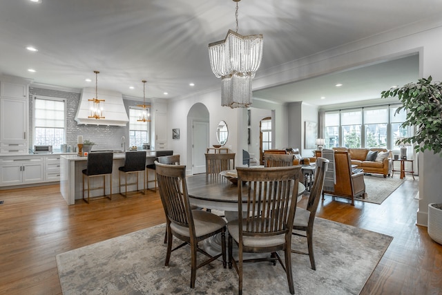 dining room with crown molding, plenty of natural light, a chandelier, and light hardwood / wood-style floors