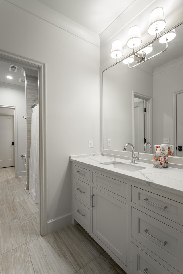 bathroom featuring a shower with shower curtain, ornamental molding, and vanity