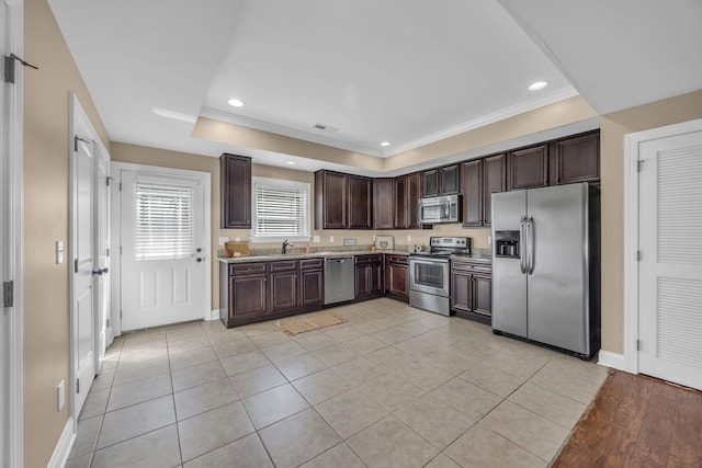 kitchen with dark brown cabinetry, light tile patterned flooring, ornamental molding, and appliances with stainless steel finishes