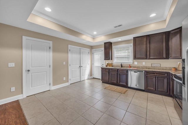 kitchen with a tray ceiling, light tile patterned flooring, stainless steel dishwasher, and ornamental molding