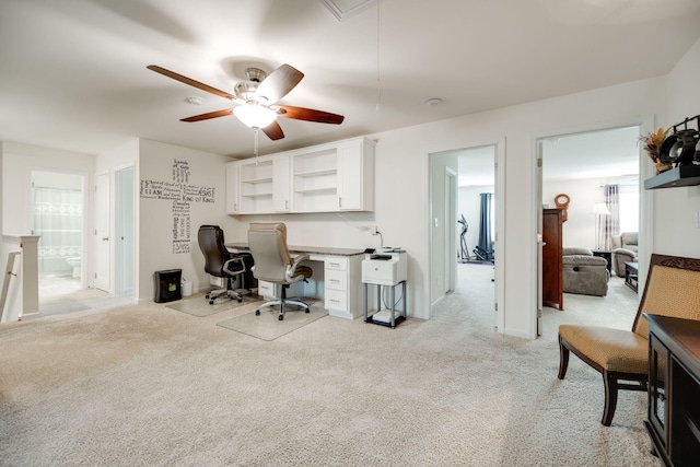 carpeted home office with built in desk and ceiling fan