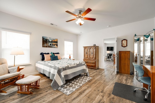 bedroom featuring wood-type flooring, multiple windows, and ceiling fan