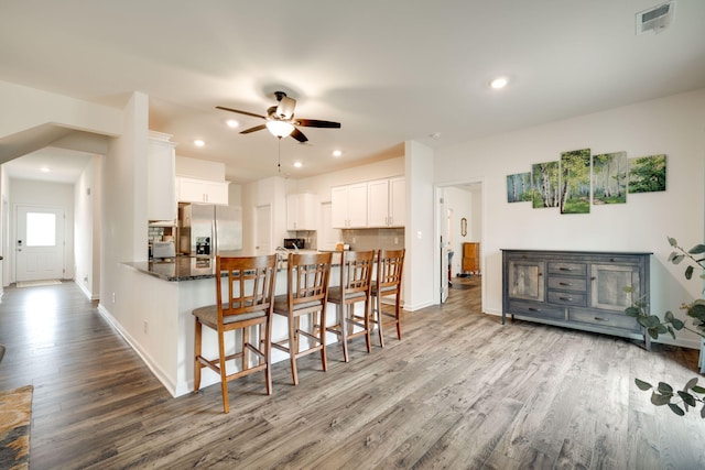 kitchen with wood-type flooring, white cabinets, kitchen peninsula, ceiling fan, and stainless steel fridge