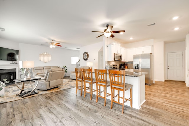 144 Ridgelake Cir Unit 122, Fort Oglethorpe, GA 30742 - kitchen with stainless steel appliances, a ceiling fan, light wood-style flooring, dark stone countertops, and white cabinetry